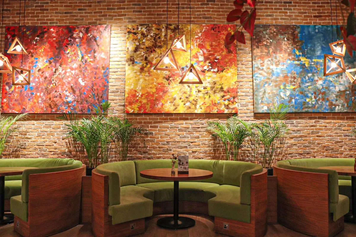 Nolu's dining room with green booths and an art wall in Abu Dhabi